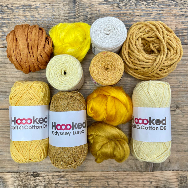 A multi-coloured yarn pack is displayed with an assortment of weaving yarn and fibre suitable as tapestry yarn, craft yarn, fiber art yarn and more. The colour way for these weaving supplies is 'Golden Solstice'.